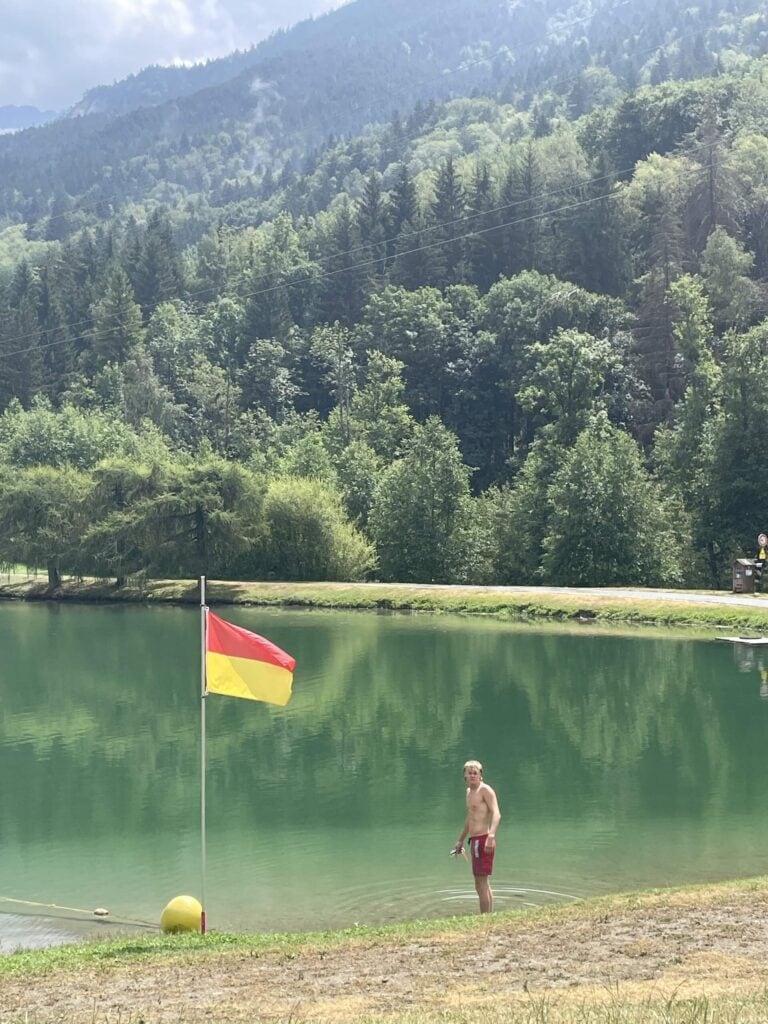 Young guest enjoying the refreshing waters of an alpine lake near Méribel during a summer holiday at La Petite Cachée in Les Trois Vallées.