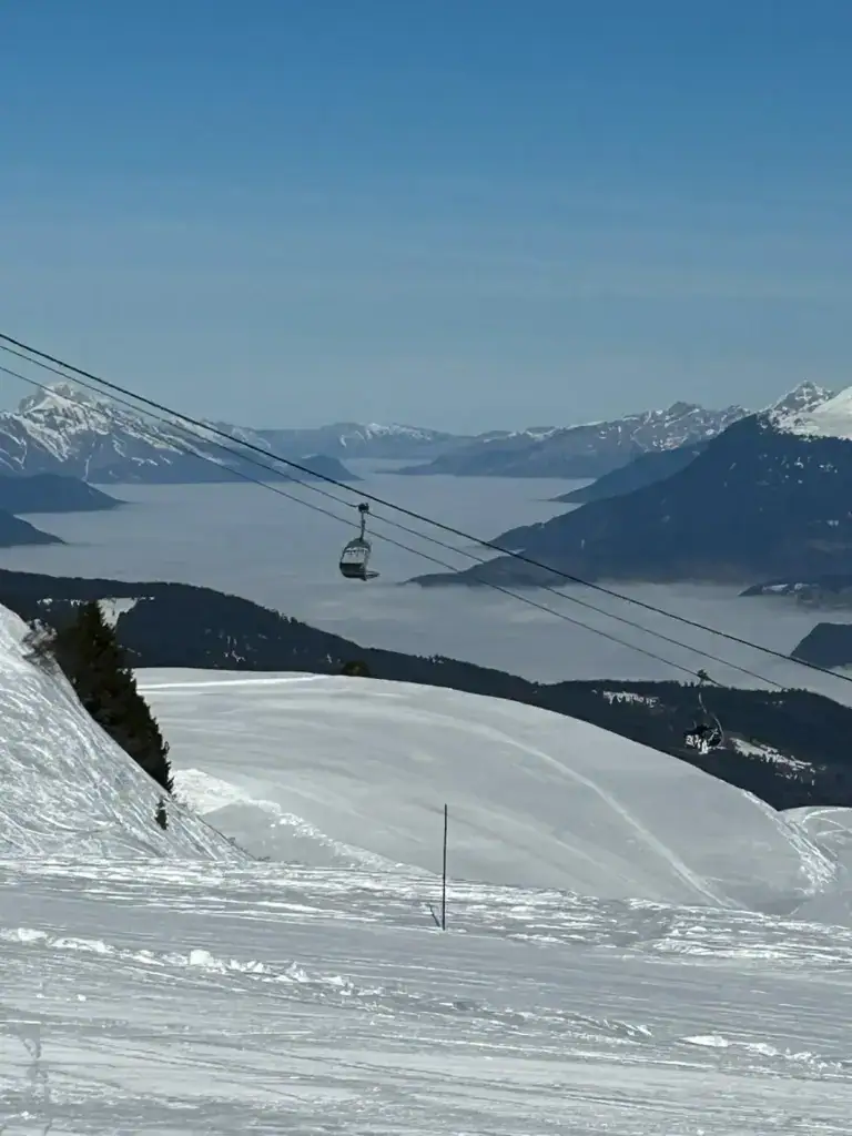 Ski lift and panoramic mountain views across the Three Valleys near Méribel during a winter holiday at La Petite Cachée.